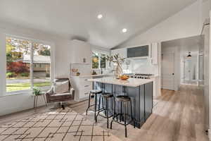 Kitchen with a kitchen island, a breakfast bar area, decorative backsplash, white cabinets, and light wood-type flooring