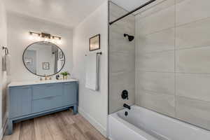 Master bathroom. Full. With hardwood / wood-style flooring, tiled shower / bath combo, and vanity