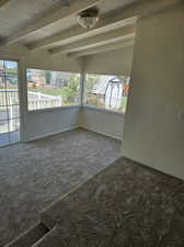 Unfurnished room with carpet floors and beamed ceiling