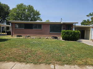 View of front facade featuring a carport and a front yard