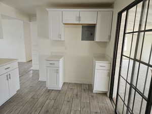 Kitchen with white cabinetry, light hardwood / wood-style floors, and electric panel