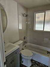 Full bathroom with toilet, tile patterned floors, tiled shower / bath combo, and vanity