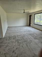 Carpeted empty room featuring a textured ceiling and ceiling fan