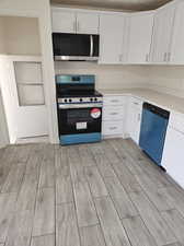 Kitchen featuring white cabinetry, light hardwood / wood-style floors, and appliances with stainless steel finishes