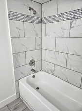 Bathroom with tiled shower / bath combo and hardwood / wood-style flooring