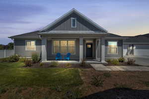 View of front of house with a porch, a garage, and a lawn