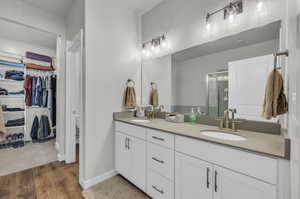 Bathroom with hardwood / wood-style floors, an enclosed shower, and dual bowl vanity