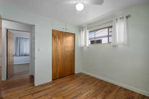 Unfurnished bedroom with ceiling fan, a closet, and hardwood floors