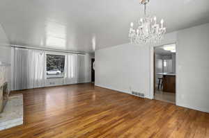 Unfurnished living room with a chandelier and hardwood floors