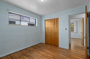 Unfurnished bedroom with wood flooring and a closet