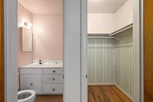 Bathroom with vanity, toilet, and wood-type flooring with master bedroom. Potential larger bathroom.