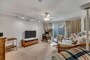 Carpeted living room featuring ornamental molding, rail lighting, and ceiling fan