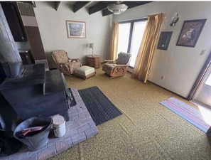 Carpeted living room featuring beamed ceiling and Wood burning stove