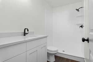 Bathroom featuring vanity, walk in shower, hardwood / wood-style flooring, and toilet. *There are options shown in this photo that would add to the price of the home*