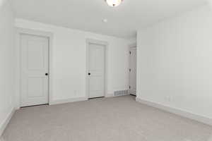 Primary bedroom with light colored carpet, walk in closet and private bathroom.