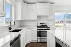 Kitchen featuring stainless steel appliances, white cabinets, sink, and island *There are options shown in this photo that would add to the price of the home*