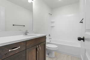 Full bathroom with wood-type flooring, bathtub / shower combination, toilet, and vanity. *There are options shown in this photo that would add to the price of the home*