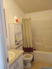 Full bathroom featuring vanity, toilet, shower / bathtub combination with curtain, and tile patterned flooring