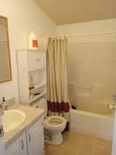 Full bathroom with vanity, tile patterned floors, toilet, and shower / bath combination with curtain