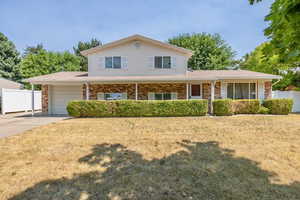 View of front of house featuring a garage, a porch, and a front lawn