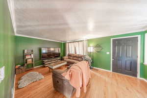 Living room with crown molding, light hardwood flooring