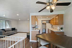 Kitchen featuring white appliances, sink, dark hardwood / wood-style floors, a textured ceiling, and ceiling fan