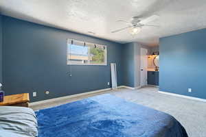 Carpeted bedroom featuring a textured ceiling and ceiling fan