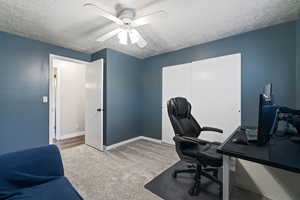 Carpeted office space featuring a textured ceiling and ceiling fan