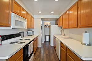 Kitchen featuring sink, dark wood-type flooring, and white appliances