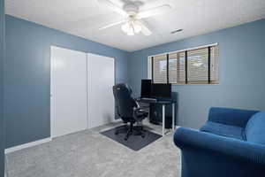 Carpeted home office featuring a textured ceiling and ceiling fan