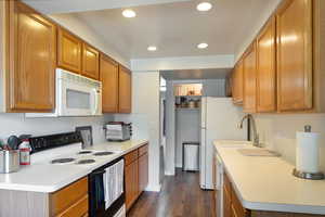 Kitchen featuring dark wood-type flooring, sink, and white appliances