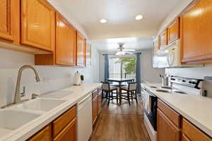 Kitchen with sink, dark hardwood / wood-style floors, ceiling fan, and white appliances