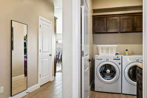 Washroom with cabinets, light hardwood / wood-style flooring, and washer and dryer