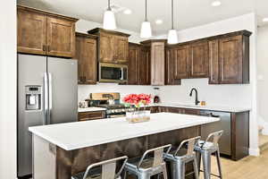 Kitchen with hanging light fixtures, sink, a breakfast bar, appliances with stainless steel finishes, and backsplash