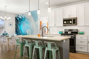 Kitchen with appliances with stainless steel finishes, hanging light fixtures, a notable chandelier, and a breakfast bar