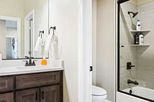 Full bathroom with vanity, enclosed tub / shower combo, and toilet