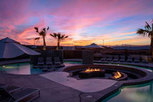 Pool at dusk featuring a patio and an outdoor fire pit