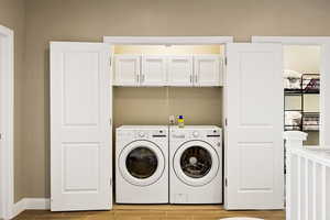 Laundry area featuring washer and clothes dryer and cabinets