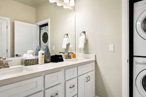 Bathroom with double sink vanity and stacked washing maching and dryer