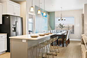 Kitchen featuring light hardwood / wood-style flooring, white cabinets, a kitchen bar, and pendant lighting