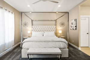 Carpeted bedroom featuring multiple windows and ceiling fan