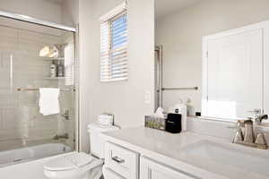 Full bathroom with vanity, toilet, and enclosed tub / shower combo