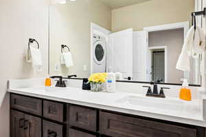 Bathroom featuring double vanity and stacked washer and clothes dryer