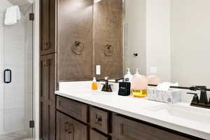 Bathroom featuring a shower with door and double sink vanity