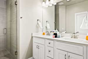 Bathroom featuring a shower with door and double sink vanity