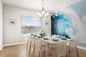 Dining space with light hardwood / wood-style floors, a wealth of natural light, and an inviting chandelier