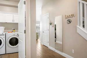 Washroom featuring washer and clothes dryer and light wood-type flooring