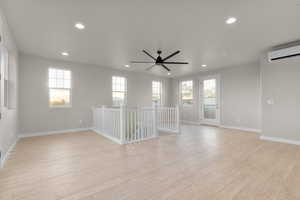 Spare room with light hardwood / wood-style floors, a wall mounted air conditioner, and a healthy amount of sunlight