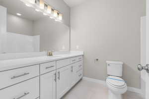 Bathroom with toilet, vanity, and tile patterned floors