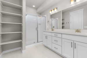 Bathroom featuring a shower with door, vanity, and tile patterned floors